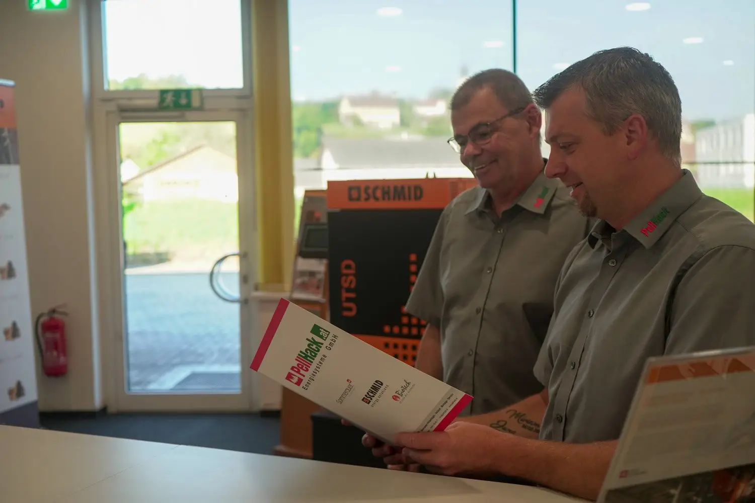 Zwei Mitarbeiter der Firma Pellhack lesen eine Broschüre