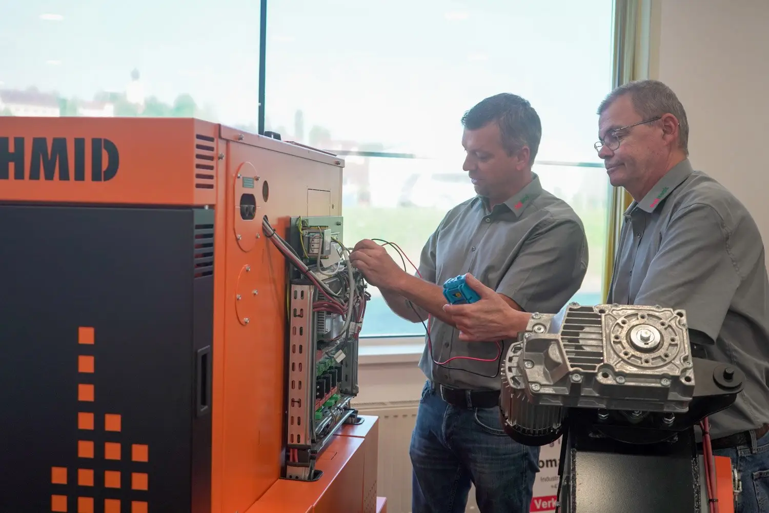 Zwei Mitarbeiter der Firma Pellhack arbeiten an einer Pelletsheizung und messen diese aus