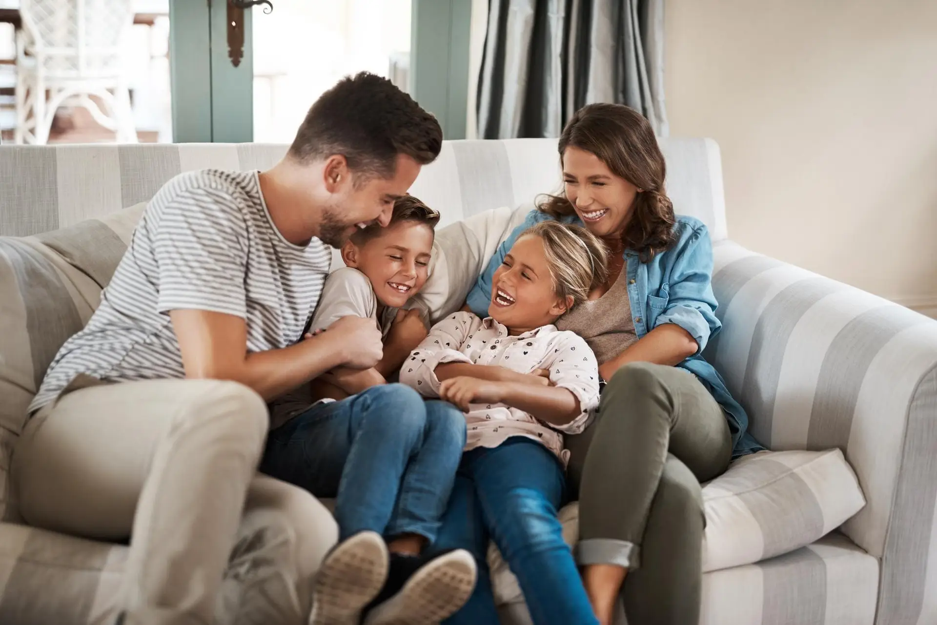 Familie lacht gemeinsam im warmen Wohnzimmer